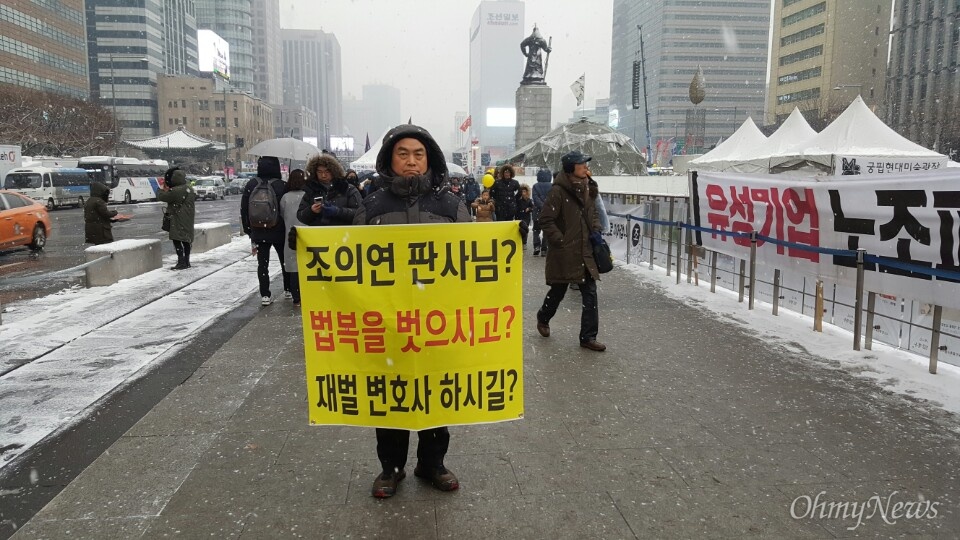  21일 서울 광화문광장에서 열리는 13번째 촛불집회에 참석한 박점보(71)씨가 '조의연 판사님, 법복을 벗으시고, 재벌 변호사 하시길'이라고 쓴 현수막을 들어보이고 있다.
