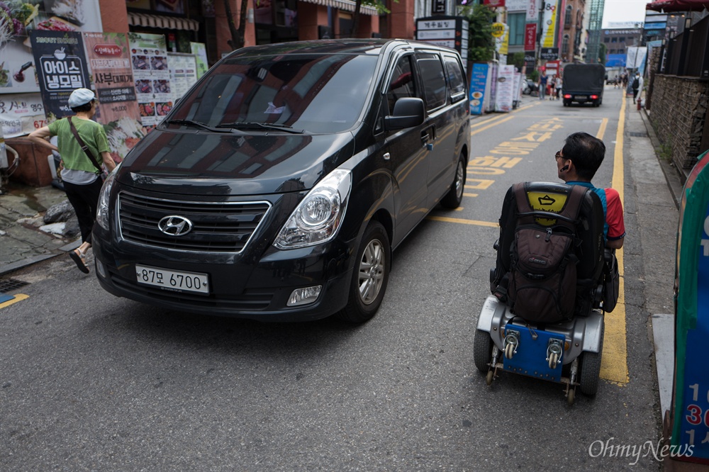  이경호씨가 14일 오후 서울 종로구 대학로에서 전동차로 이동을 하는 동안 차들이 수없이 옆을 지나갔다. 