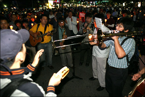 5일 밤 미국산 쇠고기 수입 반대 및 재협상 요구 촛불 거리시위대가 세종로 사거리에 도착하자 시위대를 위해 연주를 하고 있는 '시민악단'. 이들은 다음 아고라에서 조직됐다.