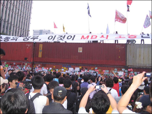 11일 새벽 컨테이너 박스 위로 올라간 시위대가 플래카드를 펼치고 있다.