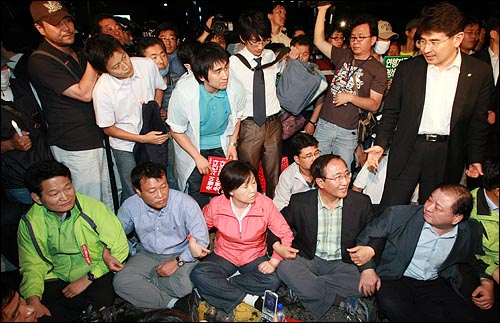 30일 새벽 서울 종로1가 도로에서 시위대와 경찰의 물리적인 충돌을 막기 위해 시위대 전면에 나와 있는 민주당 의원들과 진보신당 전 의원들이 경찰의 강제진압이 시작되자 스크럼을 짜고 버티고 있다.
