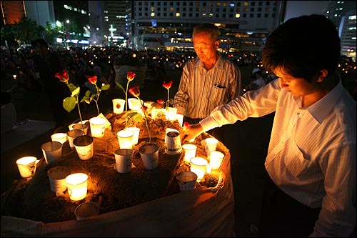 3일 밤 서울시청앞 광장에서 열린 '국민존중 선언과 평화집회 보장을 위한 기독교 시국기도회'에 참석한 시민들이 촛불과 장미꽃을 모아두고 있다.