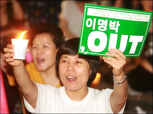 10일 저녁 서울 종로 보신각앞에서 '촛불을 지켜내려는 시민들의 모임' 주관으로 열린 촛불집회에서 한 참가자가 촛불과 함께 '이명박 OUT'이 적힌 손피켓을 들고 함성을 외치고 있다.