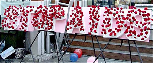 '제21회 세계 에이즈의 날'을 맞아, 'STOP AIDS' 글씨 위로 시민들이 붉은 장미꽃을 꽂았다.