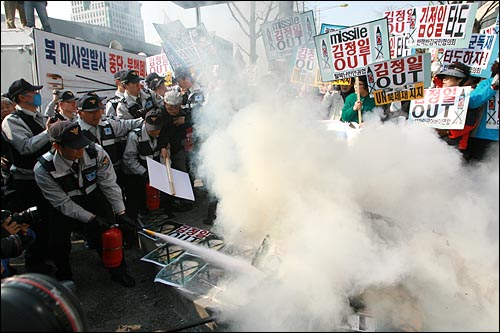 보수단체 회원들이 모형 미사일과 김정일 국방위원장 사진을 불태우는 시위를 벌이자, 경찰이 한동안 지켜보기만 하다 한참뒤에 소화기로 불을 끄고 있다.