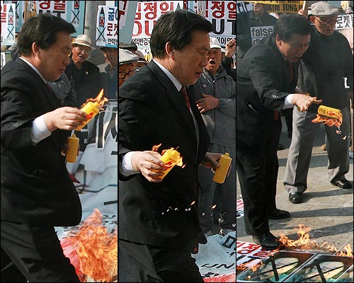 박찬성 반핵반김국민협의회 대표가 라이터 기름통에 불이 붙은줄도 모른 채 화형식에 열중하다가 깜짝 놀라 라이터 통을 던지고 있다.