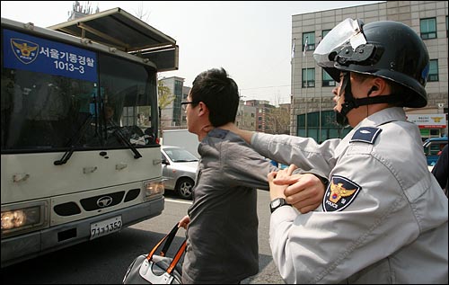 경찰이 한 대학생의 팔을 꺾고 뒷목을 잡은 채 경찰버스로 강제연행하고 있다.
