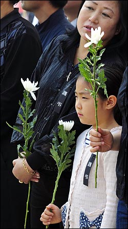 노무현 전 대통령 서거 사흘째인 25일 오전 경남 김해 봉하마을회관 앞에 마련된 분향소를 찾은 시민들이 조문을 하기 위해 국화꽃을 들고 순서를 기다리고 있다.