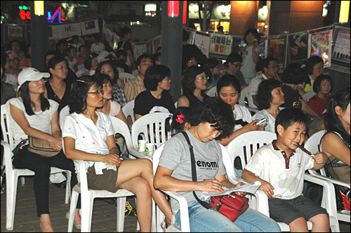 경남여성회 부설 여성인권상담소가 28일 저녁 창원 상남동 분수광장에서 마련한 '틈새 영화제'에 참석한 시민들이 앉아 있다.