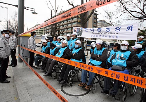 휠체어를 탄 상이군경회 회원들이 19일 오전 서울 세종로 미 대사관 부근에서 오바마 미 대통령을 태운 차량 행렬을 기다리며 경찰통제선 안쪽에서 대기하고 있다.
