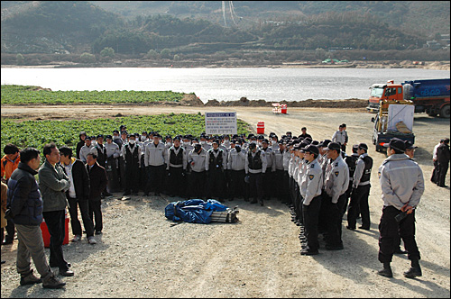 농민.환경단체가 20일 오전 4대강정비사업의 낙동강 18공구 함안보 공사 현장 입구에서 농성에 들어가기 위해 천막을 옮겨 놓은 가운데, 경찰이 천막을 에워싸고 서 있다.