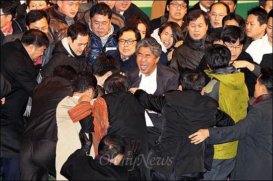 민주당이 11일 임시전국대의원대회에서 진통끝에 야권통합안 전대 가결을 선포하자 반대측 당원들이 연단에 올라 이를 저지하는 당직자들과 몸싸움을 벌이고 있다.
