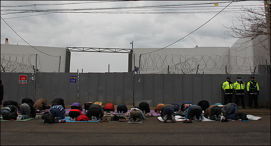 국제평화운동가들이 2월 25일 강정마을 해군기지 공사장 정문 앞에서 문정현 신부와 함께 '평화의 절'을 하고 있다.