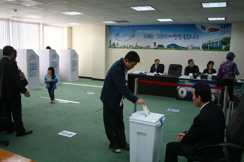 기표를 마친 유권자가 봉투에 넣어 봉한 자신의 표를 투표함에 넣고 있다.