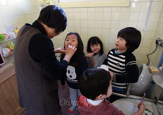25일 오후 서울 용산구 원효로 공동육아로 운영하는 '동글동글 어린이집'에서 윤은미 교사사 점심식사를 마친 아이들의 양치질을 도와주고 있다.