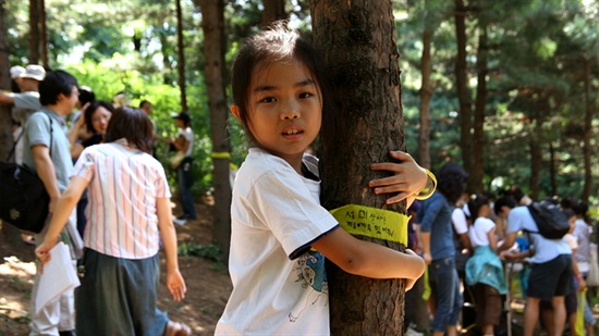  성미산의 나무를 지키기 위해 마을의 한 아이가 나무를 껴앉고 있다. 