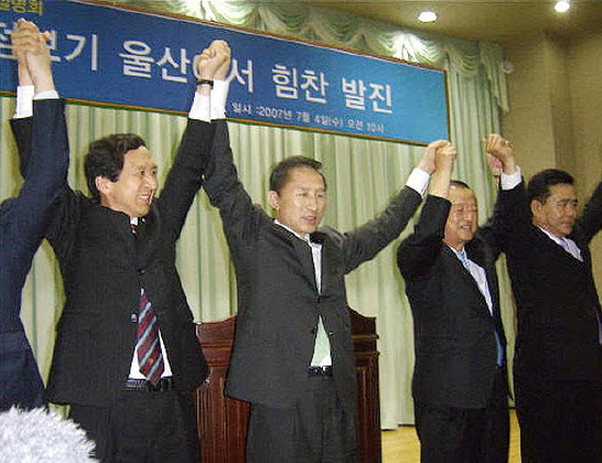 이명박 전 대통령이 2007년 7월 4일 울산상공회의소에서 연설을 한 후 지역 정치인들과 손을 맞잡고 청중들에 인사하고 있다.  