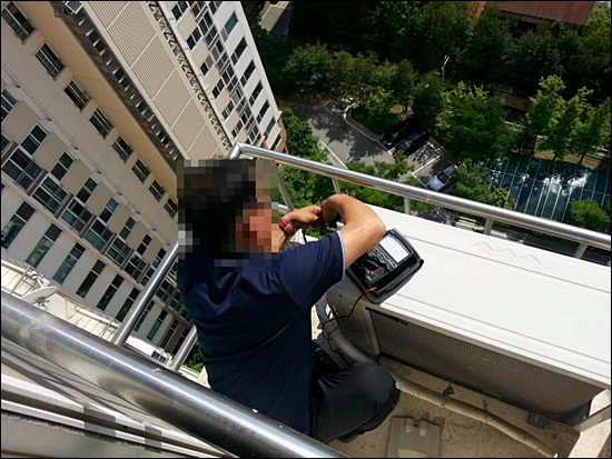 삼성전자서비스 협력업체 직원이 고층 아파트에서 에어컨 실외기를 수리하고 있다.