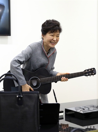 박근혜 대통령이 11월 24일 오전 전북 전주 완산구 전북 창조경제혁신센터 출범식을 마친 뒤 센터를 시찰하던 중 탄소소재로 만든 기타를 연주해 보기 위해 자리에 앉고 있다.