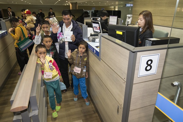 '재정착 난민제도'에 따라 2015년 12월 23일 오전 영종도 인천국제공항을 통해 입국한 미얀마인들이 입국심사를 받으며 손은 흔들고 있다. 
