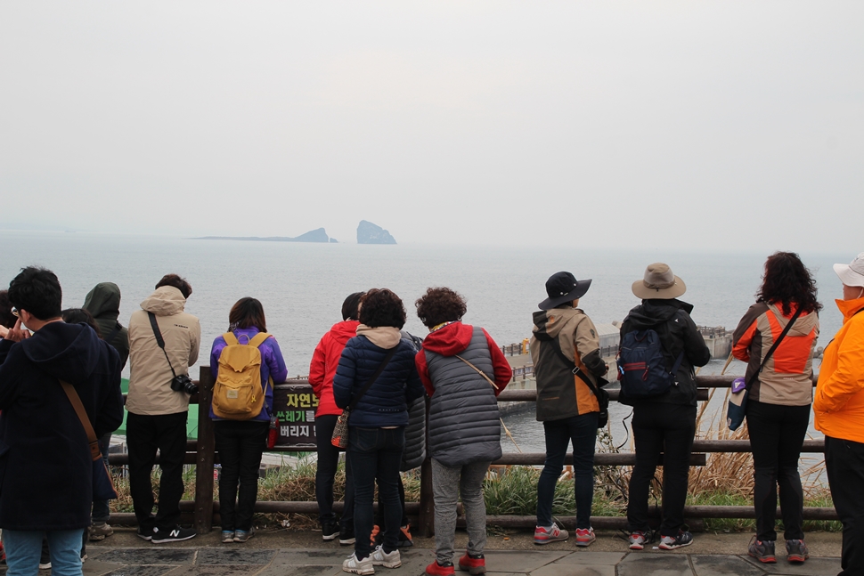  송악산 입구에서 여행자들이 형제섬을 바라보고 있다. 