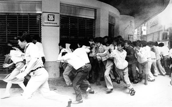 1987년 6월 13일 점심시간을 이용해 시위에 참가한 명동 주변의 회사원들을 향해 경찰이 최루탄을 발사하자 급히 자리를 피하는 모습