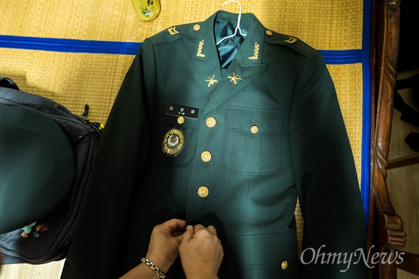 고 김준엽 하사의 엄마가 아들이 입었던 제복의 단추를 잠그고 있다. 