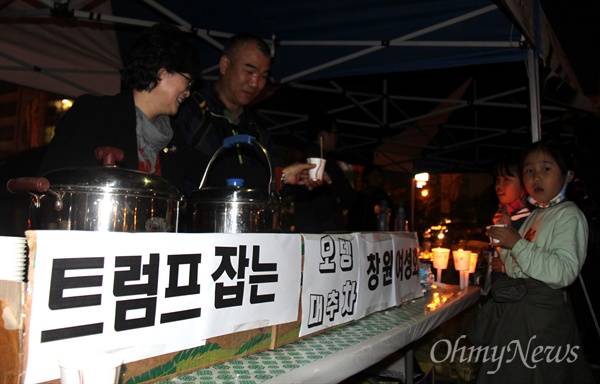  '적폐청산과 민주사회건설 경남운동본부'가 28일 저녁 창원광장에서 연 "촛불혁명 1년, 적폐청산과 사회대개혁 경남도민대회"에 참석한 시민들이 '트럼프 잡은 오뎅, 대추차'를 나눠주고 있다. 