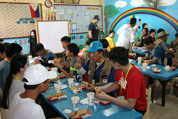  의료봉사가 진행되는 공간 인근에 식당이 없어 점심시간에 햄버거로 해결하고 있는 봉사단원들