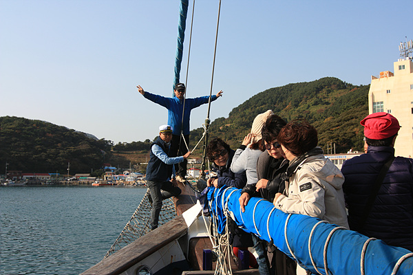  범선에 승선해 즐거워하는 참가자들이 멋진 포즈로 기념촬영하고 있다