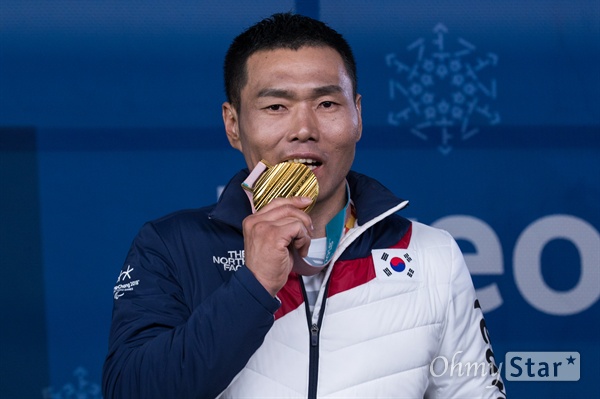  노르딕스키 신의현 선수가 17일 오후 강원도 평창 올림픽메달플라자에서 열린 크로스컨트리 남자 7.5km 좌식 부문 수상식에서 금메달을 받고 메달을 물어보고 있다.