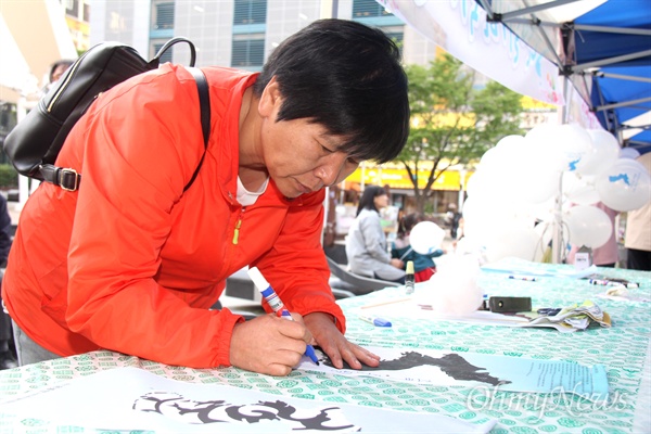  이선이(창원)씨가 25일 오후 창원 상남동 분수광장에서 열린 "남북정상회담 환영 문화제"에서 '단일기 달기'에 글을 적고 있다.