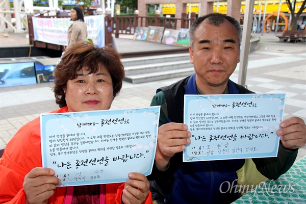  강선영(창원, 왼쪽)씨가 25일 오후 창원 상남동 분수광장에서 열린 "남북정상회담 환영 문화제"에서 '종전선언' 손팻말을 들어 보이고 있다.