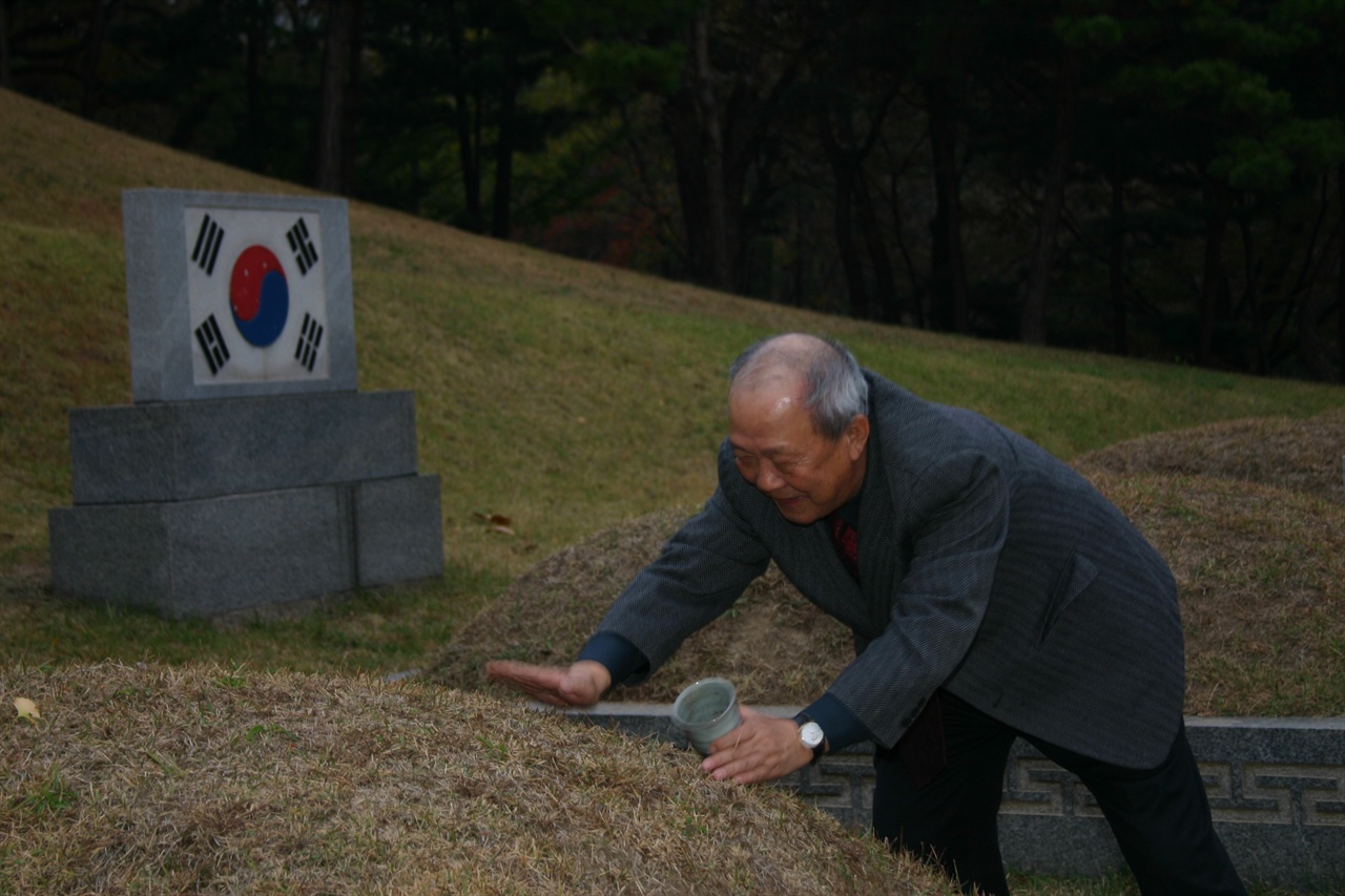 기자가 효창원에 있는 안중근 가묘 봉분에 뤼순감옥 옛 묘지에서 가지고 온 흙을 헌토하고 있다.