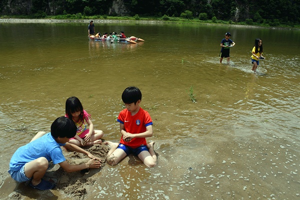  엄마·아빠의 손을 잡고 따라온 아이들이 강변 모래톱에서 모래 장난을 통해 추억을 쌓고 있다. 