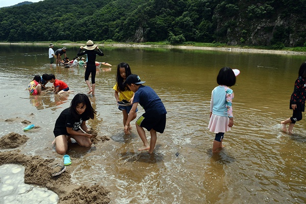  엄마·아빠의 손을 잡고 따라온 아이들이 강변 모래톱에서 모래 장난을 통해 추억을 쌓고 있다. 