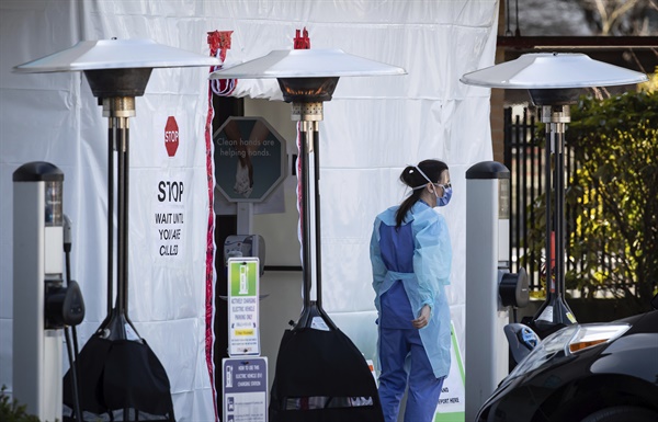 지난 19일(현지 시각), 캐나다 노스 밴쿠버에 있는 라이온스 게이트 병원의 직원이 안면 가리개와 마스크를 얼굴에 하고 임시로 마련된 코로나19 선별진료소 앞에 서 있다. 벤쿠버 지역 보건 기관에 따르면, 이 병원의 행정 직원 3명이 바이러스 양성 반응을 보였다고 한다. 