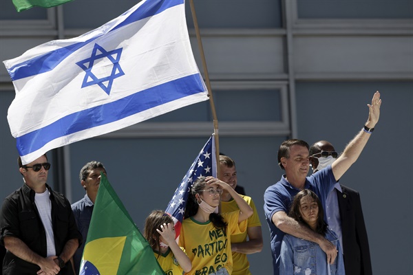  지난 3일 브라질리아의 플라날토궁 앞에서 열린 대통령 지지 시위에 딸과 함께 참석한 자이르 보우소나루 브라질 대통령이 손을 들어 인사하고 있다. 옆으로 브라질 국기와 함께 이스라엘 국기와 미국 국기가 보인다.