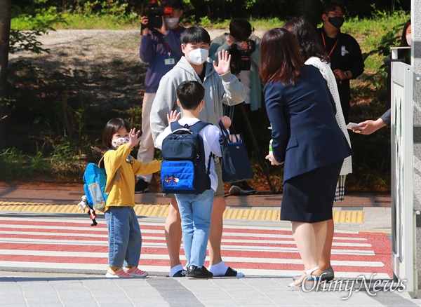  27일 오전 서울 성북구 월곡초등학교에서 1,2학년 학생들이 코로나19 여파로 인해 미뤄진 등교를 시작하고 있다. 한 학생이 교실로 들어가기 전 아빠, 동생과 손을 흔들며 인사를 나누고 있다. 지난 20일 고3에 이어 27일에는 고2, 중3, 초1,2 학생들이 등교수업을 시작했다.