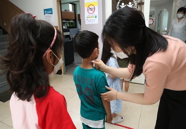  지난 5일 강남구 관내 한 유치원에서 선생님이 아이들에게 ‘붙이는 체온계’를 착용해 주고 있다.