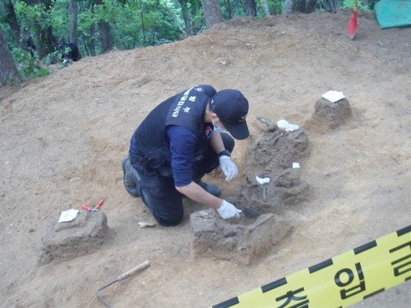 2012년 6월, 강원도 인제에 위치한 명당산 유해발굴현장에서 유해를 수습하고 있는 국방부 유해발굴감식단 소속 발굴병의 모습