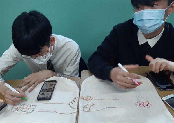  두 학생은 공동작업으로 통일을 표현했다. 각자 그린 에코백 그림을 나란히 맞대면 둘이 손을 잡는 그림이 나타난다.