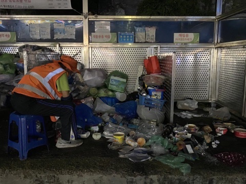  춘천 교동의 한 집하장에서 지킴이가 의자에 앉아 쓰레기를 정리하고 있다.