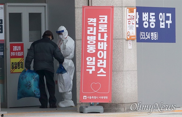 이불과 소지품을 챙겨온 시민이 2020년 12월 11일 오전 서울 은평구 서울시립서북병원에서 방호복을 입은 의료진의 안내를 받으며 격리병동으로 들어가고 있다. 