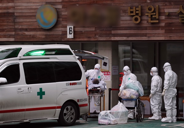  29일 오후 서울 구로구의 한 요양병원에서 코로나19 확진자가 거점전담병원으로 이송되기 위해 구급차로 옮겨지고 있다.