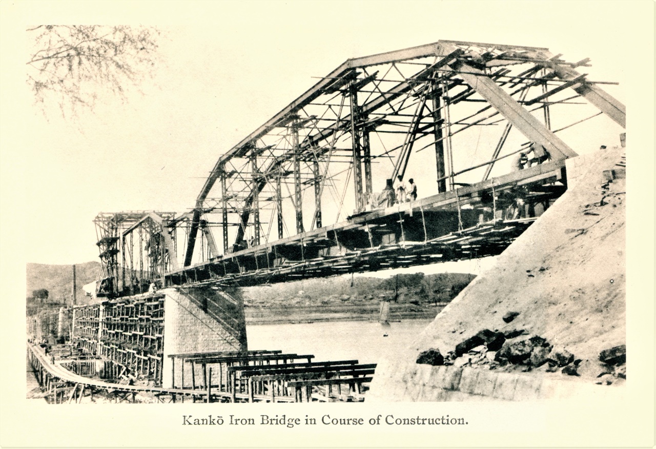 한강철교 건설장면 교각 사이에 임시가설물(벤트)을 올리고 그 위에서 곡형 와렌 트러스를 강결시키는 장면이 뚜렷하다. 1899~1900년 사이로 추정되는 모습이다.