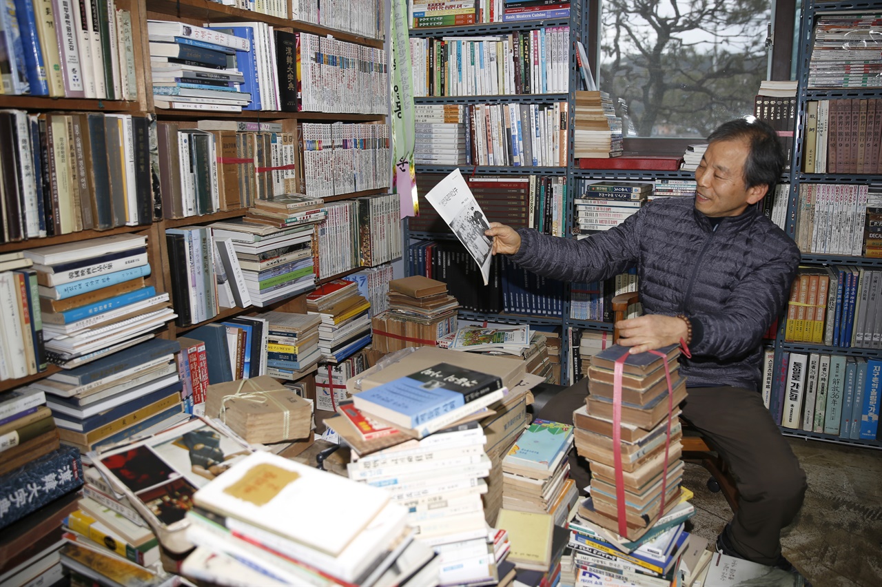  책을 진열하던 김종훈 책방지기가 오래 된 자료집을 하나 들어보이고 있다.