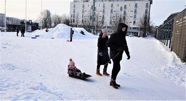  눈썰매에 아이를 태우고 거리를 누비는 핀란드인 부모들과 눈썰매를 타는 배경의 아이들