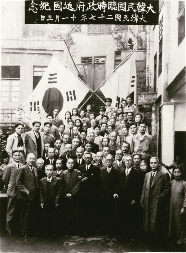  일본의 패망 뒤, 귀국을 앗두고 임정 요인들이 청사 계단에 서서 마지막 기념 촬영을 했다. 뒤에 세운 대형 태극기가 슬프다. 1945년 11월 3일.