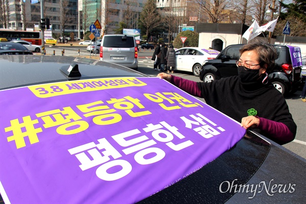 김윤자 경남여성단체연합 대표가 3월 8일 오전 경남도청 앞에서 차량에 '세계여성의날' 관련 손펼침막을 부착하고 있다.